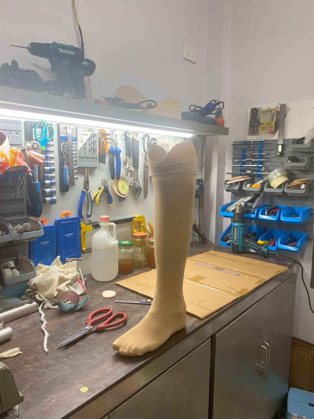 A below-knee prosthesis being made in the workshop: a socket made individually, connected to the pylon and prosthetic foot.
