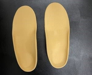 A left–right pair of orthotic insoles side by side: seen from above, the arch support is visible on the inner side of the sole.
